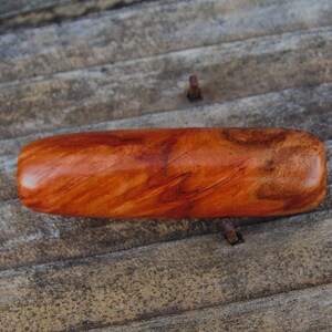 May include: A smooth, reddish-brown wooden cylinder with a natural wood grain pattern.