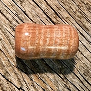 Puede incluir: Un pomo de madera liso de color marrón claro con un patrón de veta en espiral.