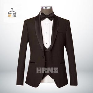 May include: A dark brown tuxedo suit with a black satin lapel and a black bow tie. The suit includes a matching vest. The text "HRMZ" is printed on the vest.