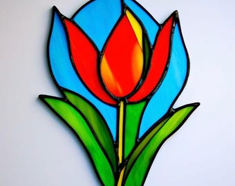 May include: A stained glass tulip with red petals, yellow centre, green leaves, and a blue background.