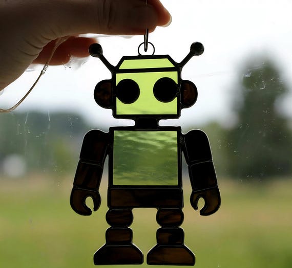 Hand-cut stained glass robot suncatcher with a retro sci-fi silhouette — classic craft technique meets geek iconography in a way that glows.
