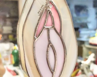May include: A stained glass pendant in the shape of a teardrop with a pink and white design. The pendant is made of glass and has a silver wire frame.