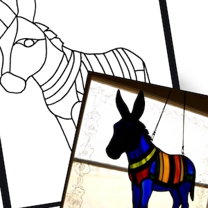 May include: A stained glass donkey suncatcher with a blue body and a colorful striped blanket. The donkey is hanging in front of a window. A black and white line drawing of a donkey is in the background.