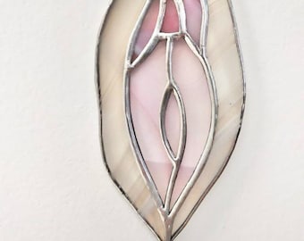 May include: A stained glass window hanging ornament featuring a pink and white abstract design. The design is reminiscent of a flower or a leaf.