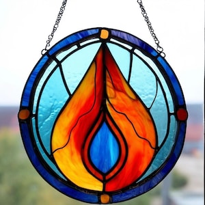 May include: A stained glass window hanging from a chain. The design is a circular frame with a blue background and a yellow, orange, and red flame in the centre. The flame has a blue teardrop shape in the centre.