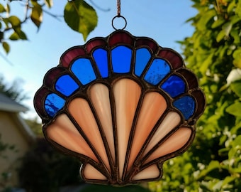 May include: A stained glass seashell suncatcher with a pink and white shell and a blue and purple border.
