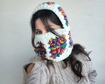 May include: A white crochet balaclava with a colorful floral design. The balaclava covers the head and neck, with an opening for the eyes. The colorful design includes red, yellow, blue, and green. The balaclava is handmade and appears to be warm.