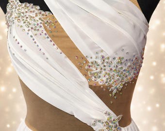 Puede incluir: Un vestido de baile blanco con corpiño drapeado, paneles de malla color nude, escote asimétrico y tirantes finos. La prenda está adornada con grupos de cristales iridiscentes dispuestos en patrones florales en la parte delantera.