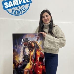 May include: A framed art print featuring a jazz-themed illustration. The artwork depicts a man in a hat and a woman playing a double bass. The print has a glossy finish and is held by a person. The print has a blue stamp that says "SAMPLE".