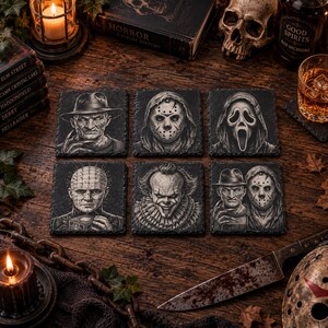 May include: A set of six square slate coasters featuring detailed black and white illustrations of iconic horror movie characters, including a man with a fedora and clawed hand, a hockey mask, a ghost mask, a pin-headed figure, and a clown.