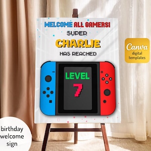 May include: A white sign on a wooden easel with the text "WELCOME ALL GAMERS! SUPER CHARLIE HAS REACHED LEVEL 7". The sign features a graphic of a blue and red game controller. A Canva digital templates logo is in the upper right corner.