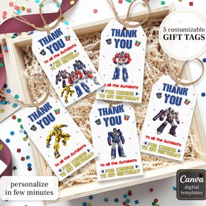 May include: Five white gift tags with brown twine, featuring Transformers characters and the text "Thank You." The tags are inside a wooden box with confetti. Text on the tags reads "to all the Autobots for coming to my birthday."