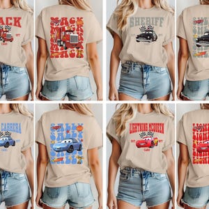 May include: Tan t-shirts with various Cars movie character designs. The designs include Mack, Sheriff, Sally Carrera, and Lightning McQueen, each with text and car illustrations. The shirts are short-sleeved.