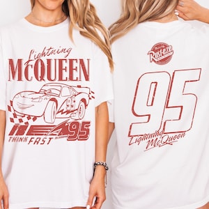 May include: White t-shirt with a red graphic of Lightning McQueen from the Cars film. The front design includes the text "Lightning McQueen," a race car illustration, and "95." The back displays "95" and "Lightning McQueen."