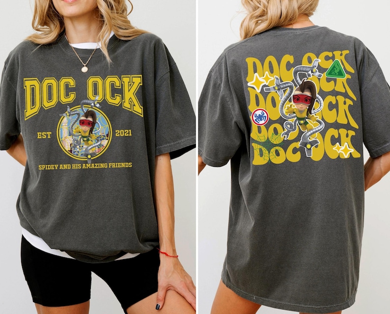 May include: Dark gray t-shirt with a yellow "DOC OCK" graphic on the front and back. The front graphic includes a circular image of a cartoon character and the text "EST 2021" and "SPIDEY AND HIS AMAZING FRIENDS". The back has a repeating "DOC OCK" design.