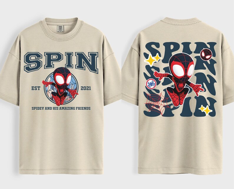 May include: Beige t-shirt featuring a graphic of a superhero character. The front of the shirt has the word "SPIN" above a circular design with the character and the text "EST 2021 Spidey and his amazing friends". The back of the shirt has the word "SPIN" repeated with the character.