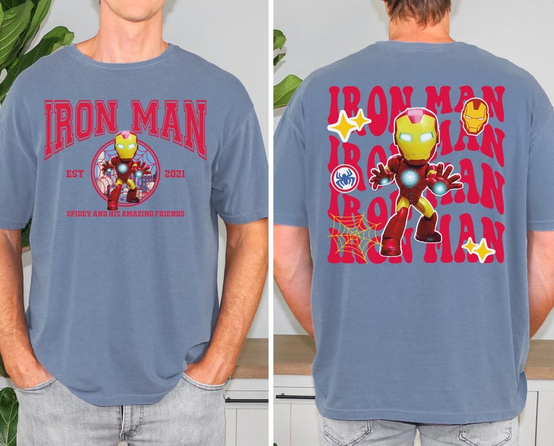 May include: A blue t-shirt featuring the Iron Man character. The front of the shirt has the words "Iron Man" in red, with a graphic of Iron Man in the center. The back of the shirt repeats "Iron Man" in red, with additional graphics.