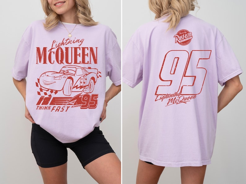 May include: Pale purple t-shirt with a red Lightning McQueen design. The front shows the car, text, and the number 95. The back of the shirt has the number 95 and the text "Lightning McQueen".