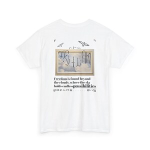 May include: White t-shirt with a framed image of a sky with clouds and birds. The text "Freedom is found beyond the clouds, where the sky holds endless possibilities" is printed below the image. The text "DREAM... BIG" is printed below the text.