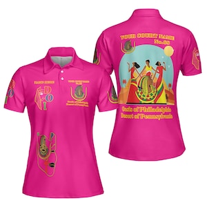 May include: A bright pink polo shirt with a collar and buttons. The shirt features Egyptian-themed graphics and text, including "YOUR COURT NAME No.08" and "Oasis of Philadelphia Desert of Pennsylvania."