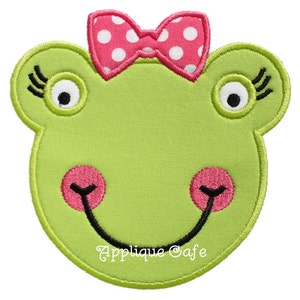 May include: Green frog face applique with pink polka dot bow, black eyelashes, and a smiling mouth. The applique is made of felt and is perfect for adding a whimsical touch to any project.