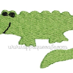 May include: Green embroidered alligator applique with black eyes and a smile. The applique is perfect for adding a whimsical touch to crafts and projects.