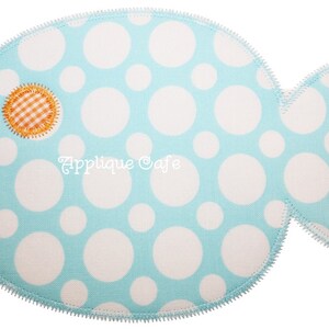 May include: A light blue fish applique with white polka dots and a small orange and white gingham eye. The fish has a scalloped edge and is perfect for sewing projects.