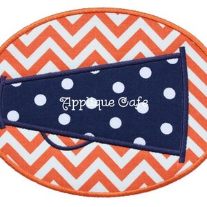 May include: An oval-shaped patch with a white and orange chevron pattern. The patch features a blue megaphone with white polka dots and the text "Applique Cafe".