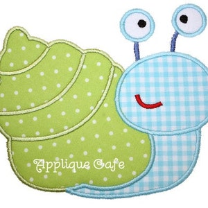 May include: A green and blue applique snail with a white polka dot shell and a blue and white checkered body. The snail has two large blue eyes and a red smile.