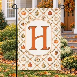 May include: A rectangular garden flag featuring a large orange letter H centered within a decorative frame. The background displays a diamond lattice pattern filled with illustrations of pumpkins, acorns, autumn leaves, and small flowers.