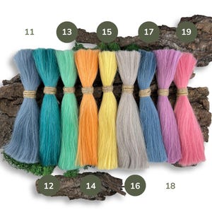 Peut inclure: Dix brins de fil de couleur disposés en rangée sur une surface en bois, numérotés de 11 à 19. Les couleurs du fil sont : turquoise, vert, orange, jaune, gris, bleu, rose et rose clair.