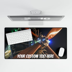 May include: A custom desk mat with a close-up image of an airplane propeller. The propeller is made of wood and metal and has a dark background. The text "YOUR CUSTOM TEXT HERE" is printed on the mat.