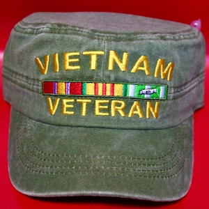 Könnte beinhalten: Olivgrüne Militärkappe mit goldfarben gesticktem Text "VIETNAM VETERAN". Unter dem Text ist ein farbenfrohes Bandemblem aufgestickt. Die Kappe hat ein strukturiertes Design mit flachem Schirm.