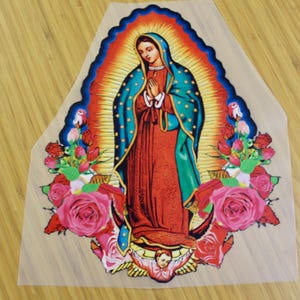 May include: A colorful iron-on patch featuring a depiction of the Virgin Mary with a halo, surrounded by roses and a cherub. The Virgin Mary is wearing a blue robe with gold stars and a red dress.