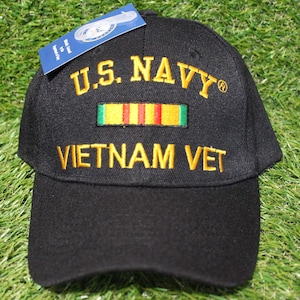 May include: Black baseball cap with the text "U.S. NAVY" and "VIETNAM VET" embroidered in yellow. A yellow, red, and green ribbon is embroidered above the text.