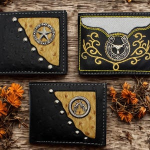 May include: Three black leather wallets with western-themed designs. One wallet features a silver star emblem, another a horseshoe, and the third a pair of crossed revolvers. Each wallet has a textured leather finish and decorative stitching.