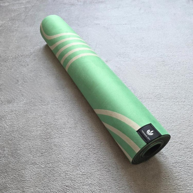 May include: A rolled up green yoga mat with white stripes and a black label that says "Namast&eacute; Yogi".