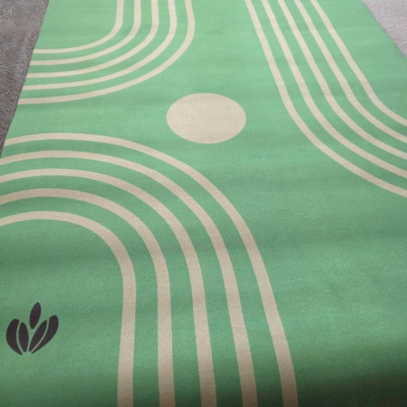 May include: Green yoga mat with a pattern of tan concentric circles and a tan circle in the center. The mat has a small, dark green logo in the lower left corner.