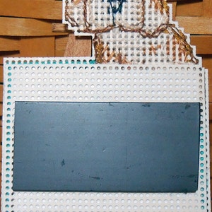 A photo of the back of the magnet. The square portion has a second layer of perforated paper attached with a piece of card stock sandwiched in between. The magnet itself covers the middle of the square portion. The dog is unlined.