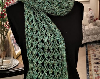 May include: A green and blue crocheted scarf with a lacy pattern. The scarf is draped over a black mannequin.