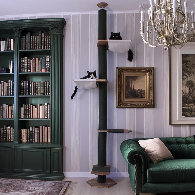 May include: A tall, dark green cat tree with multiple platforms and a scratching post. Two cats are resting in the white cat beds. The cat tree is in a room with a green bookshelf, a green sofa, and a chandelier.