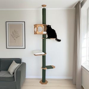 Può includere: Un albero per gatti verde con una casetta in legno e più piattaforme. Un gatto nero è appollaiato su una delle piattaforme. L'albero per gatti ha una base e dettagli in legno naturale. Le piattaforme hanno morbidi cuscini bianchi. Un accessorio elegante per gatti.