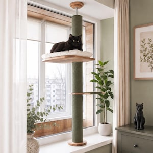 Pode incluir: Uma árvore para gatos do chão ao teto com um poste vertical central envolto em corda de sisal verde-oliva, duas plataformas de madeira e uma almofada branca. Um gato preto descansa na plataforma superior deste móvel para gatos de tensão.