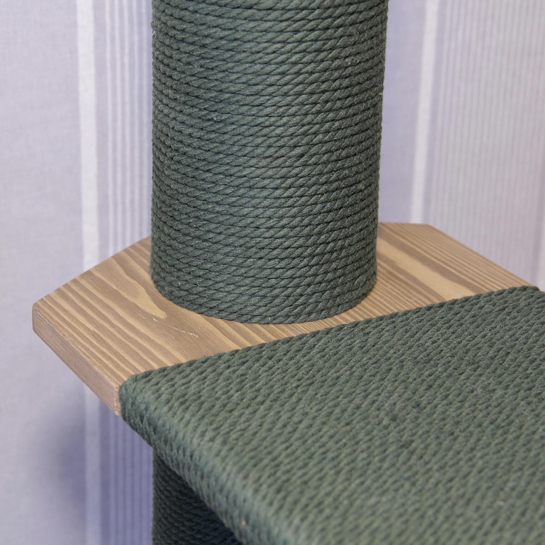 May include: Close-up of a green sisal-covered cat scratching post with a wooden platform. The post is wrapped in thick, tightly woven sisal rope.