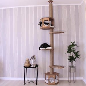 May include: A tall wooden cat tree with multiple platforms and a scratching post. The cat tree has a hexagonal base with a cushion and a small window. There are two black cats on the platforms.