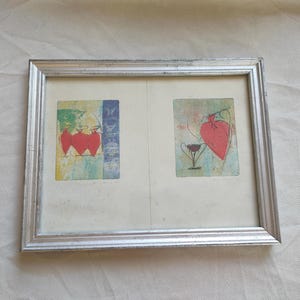 Peut inclure: Œuvre d'art encadrée avec deux panneaux aux motifs abstraits colorés. L'un montre trois cœurs rouges, l'autre un cœur et un verre de vin. Le cadre est argenté.