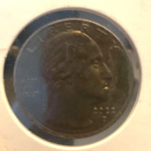 May include: A close-up of a United States quarter coin. The coin features a profile of a person on the obverse side, with the word "LIBERTY" above. The year "2022" is visible below the profile.