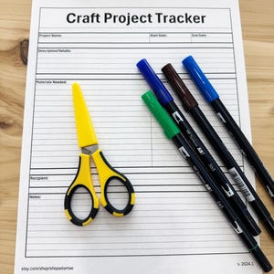 May include: A printable craft project tracker with sections for project name, start date, end date, description, materials needed, recipient, and notes. The tracker is on a white sheet of paper with a yellow pair of scissors and four black markers with coloured caps.