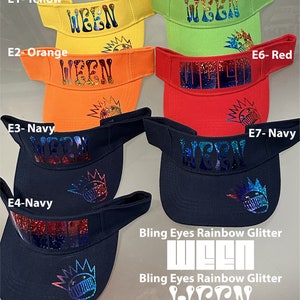 May include: Seven different colored visors with the word "WEEN" printed on them in a rainbow glitter font. The visors are in the colors yellow, orange, navy, lime, red, and two navy visors. The bottom two visors have the words "Bling Eyes Rainbow Glitter" printed below the word "WEEN".