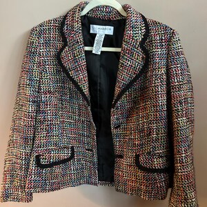 May include: A multi-colored tweed blazer featuring a textured weave of red, blue, yellow, and white threads. The jacket has a black trim along the lapels and two front pockets, a black interior lining, and a white label reading SAG HARBOR.